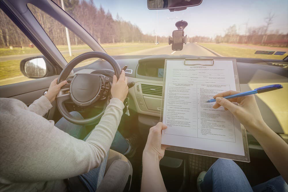 Driver and examiner reviewing a road test form inside a car